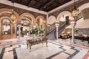 a living room with a staircase and a table with flowers on it at Hotel Alfonso XIII, a Luxury Collection Hotel, Seville in Seville
