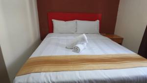 a bed with a red headboard with a towel on it at Hotel Wings Kuala Lumpur in Kuala Lumpur