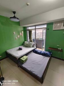 a bedroom with a large bed in a green room at Cubao Manhattan Heights Residential Condo TB30N - High Floor Studio with Balcony City View, Pool, Netflix, 5-Min Walk to the Araneta Coliseum Gateway Mall SM - Staycations by SMS in Manila