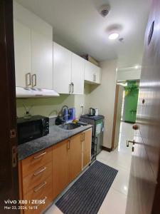 a kitchen with a sink and a microwave at Cubao Manhattan Heights Residential Condo TB30N - High Floor Studio with Balcony City View, Pool, Netflix, 5-Min Walk to the Araneta Coliseum Gateway Mall SM - Staycations by SMS in Manila