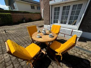 a wooden table with yellow chairs on a patio at Charmant T2 avec Terrasse et Parking Privé, Tout Confort, Proche Trouville - FR-1-712-88 in Touques