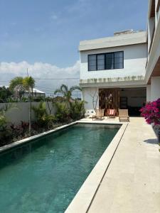 a swimming pool in front of a house at Paddy's House Seseh in Canggu