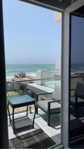 a balcony with a table and chairs and the ocean at bh villa in Al Sharqiyah