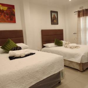 two beds in a hotel room with towels on them at Elegant BnB in Bulawayo