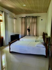 a bedroom with two white beds and curtains at ECO Canal Suite in Polonnaruwa