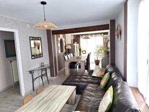 a living room with a leather couch and a table at Le roseau À plumes in Draize