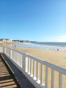 a beach with a white fence and the ocean at charmante studette a quiberon plage in Quiberon +3 photos