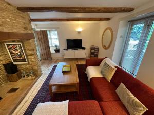 a living room with a red couch and a table at Cotswold Cottage in Steeple Aston