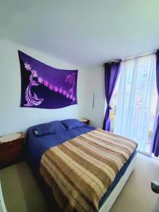 a bedroom with a bed and a purple blanket at Acogedor departamento veraneo a pasos de la avenida del Mar in La Serena