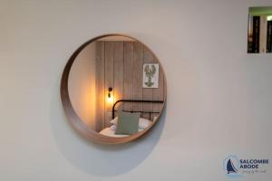 a round mirror on a wall with a bed in a room at The Hideout-Boutique Cabin, Estuary View & Parking in Salcombe +11 photos