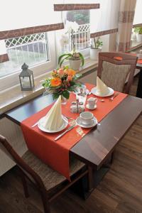 einen Esstisch mit einer roten Tischdecke und Blumen darauf in der Unterkunft Pension Haus Waldfrieden, MeineCardPlus inklusive in Willingen