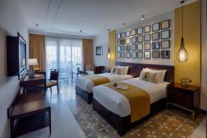 会安Allegro Hoi An . A Little Luxury Hotel & Spa的有两张床和一台电视的酒店房间