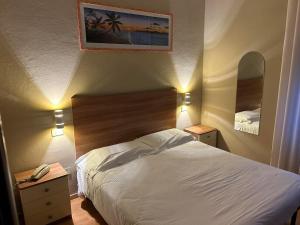 a bedroom with a bed and two nightstands and two mirrors at Piccolo Hotel in Rosignano Solvay