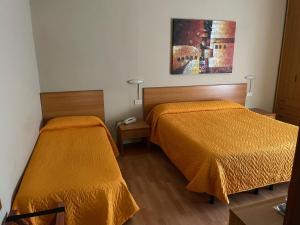 two beds in a room with orange sheets at Piccolo Hotel in Rosignano Solvay