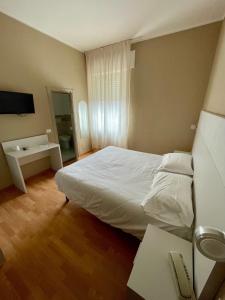 a bedroom with a white bed and a television at Piccolo Hotel in Rosignano Solvay