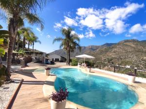 una piscina con palmeras y montañas al fondo en Casa Rural Caserío Las Viñas, en Guájar Fondón