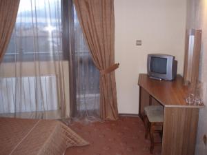 Habitación con TV, escritorio de madera y ventana. en Guest House Valevicata, en Bansko