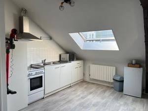 a kitchen with white cabinets and a skylight at Studio fécamp in Fécamp