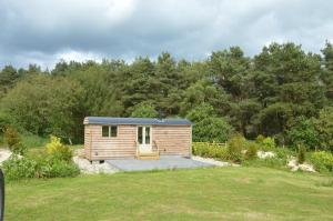 a small wooden cabin in a yard with trees at Middlehead Huts in Newton