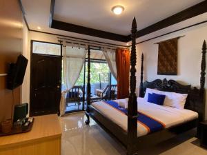 a bedroom with a canopy bed and a balcony at New Adirama Beach Hotel in Lovina