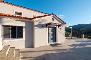 a white house with a door and mountains in the background at AEGEAN HORIZON villa in Karlovasi