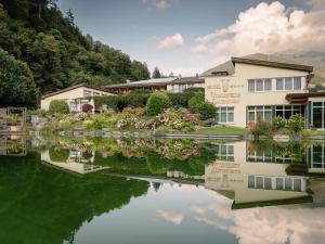 a house and its reflection in a body of water at Hotel Vitalquelle Montafon in Schruns