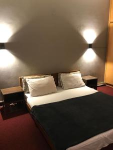 a bedroom with a large bed with two lamps on the wall at Durrani Lodges - G11 Islamabad in Islamabad +10 photos