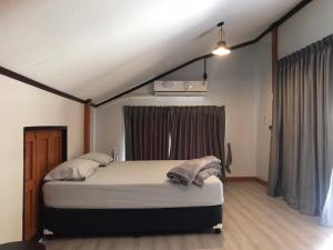 Un dormitorio con una cama y una ventana. en 66 Baanaisuan 66 บ้านในสวน, en Ban Komo Sam Sip Paet