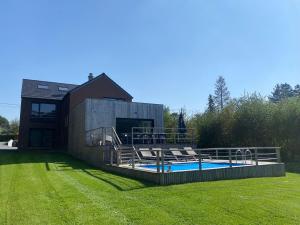 a house with a swimming pool in the grass at La villa M in Sart-lez-Spa