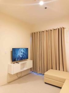 a living room with a flat screen tv and curtains at Matina Enclaves 2BR with Wifi Near SM Mall in Davao City