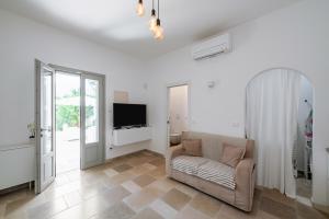 a living room with a couch and a tv at Libertini 21 by Rentbeat in Villanova di Ostuni