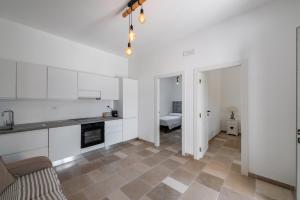 une cuisine avec des armoires blanches et un salon dans l'établissement Libertini 21 by Rentbeat, à Villanova di Ostuni 23 autres photos