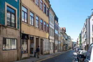 a man walking down a city street with buildings at Doispontozero Alegria Green in Porto