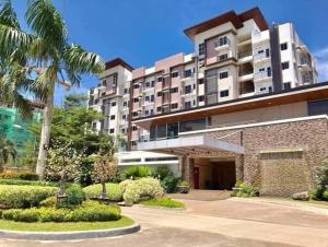 a large building with a palm tree in front of it at Matina Enclaves 2BR with Wifi Near SM Mall in Davao City