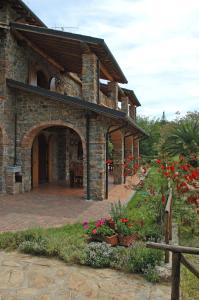 una casa de piedra con flores en un patio en Agriturismo Podere Gozzuto, en Gavorrano