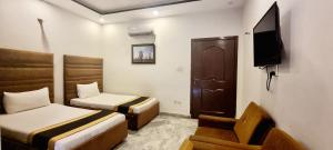 a room with two beds and a chair and a tv at Pakeeza One Hotel in Lahore