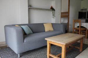 a living room with a blue couch and a table at Le Petit Gîte in Les Essarts