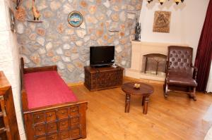 ein Wohnzimmer mit Fernseher und Steinwand in der Unterkunft Castelo Boutique Hotel in Panteli