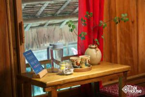 a wooden table with cups and other items on it at Thai House Pu Luong - Century Old Stilt House with Terrace Views in Hương Bá Thước
