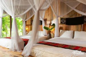 une chambre avec deux lits avec rideaux dans l'établissement Thai House Pu Luong - Century Old Stilt House with Terrace Views, à Hương Bá Thước 110 autres photos
