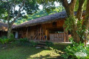 a large wooden house with a grass roof at Thai House Pu Luong - Century Old Stilt House with Terrace Views in Hương Bá Thước
