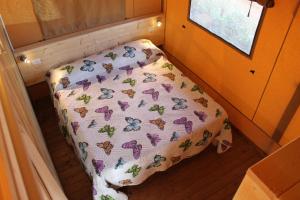 a bed in a small room with a blanket with butterflies at Il Girasole Country Village in Massignano