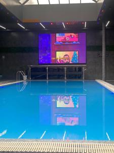 a swimming pool with a tv and a large swimming pool at MaxWell Hotel & SPA in Tashkent
