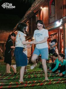 two women are standing next to a group of people at Thai House Pu Luong - Century Old Stilt House with Terrace Views in Hương Bá Thước