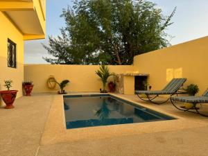 a swimming pool in a backyard with two lawn chairs and a patio at Villa à Malicounda 3 chambres, piscine, calme et confort à 10 min de Saly in Malikounda