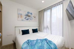 a white bedroom with a large bed with blue pillows at Sky Park condo 1 bedroom in Laguna Phuket +15 photos