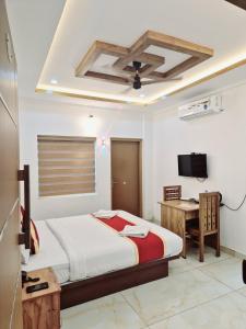 a bedroom with a bed and a desk and a television at MARINA SUITES AIRPORT HOTEL in Cochin