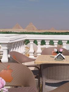 un patio al aire libre con mesas y sillas en el balcón en Pyramids High View Inn, en Giza