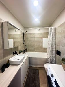 a bathroom with a sink and a tub and a toilet at Middle street apartment in Alūksne +3 photos