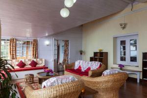 a living room with wicker chairs and a red couch at Yule Tea Retreat, Darjeeling in Sukhia Pokhari